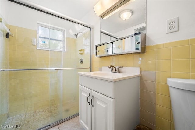 bathroom featuring vanity, tile patterned floors, toilet, tile walls, and walk in shower