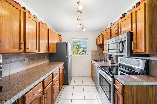 kitchen featuring appliances with stainless steel finishes, backsplash, light tile patterned floors, and sink