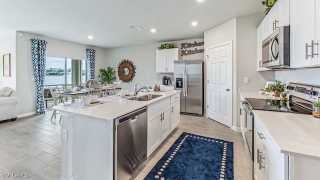 kitchen featuring stainless steel appliances, sink, white cabinets, light hardwood / wood-style floors, and an island with sink