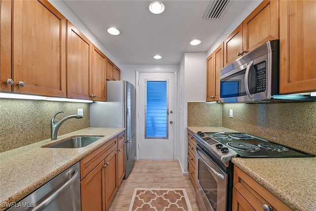 kitchen featuring backsplash, sink, light hardwood / wood-style floors, and stainless steel appliances