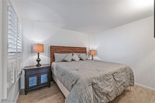 bedroom with a textured ceiling and light hardwood / wood-style flooring