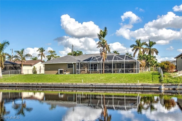 rear view of property featuring a yard, a water view, and a lanai