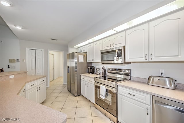 kitchen featuring light tile patterned flooring, white cabinets, and stainless steel appliances