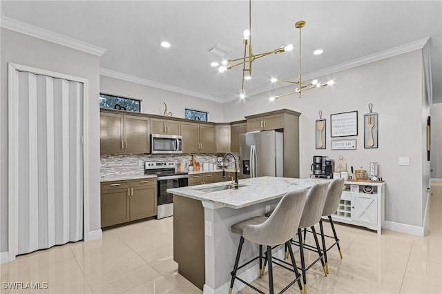 kitchen featuring light stone counters, crown molding, stainless steel appliances, sink, and an island with sink