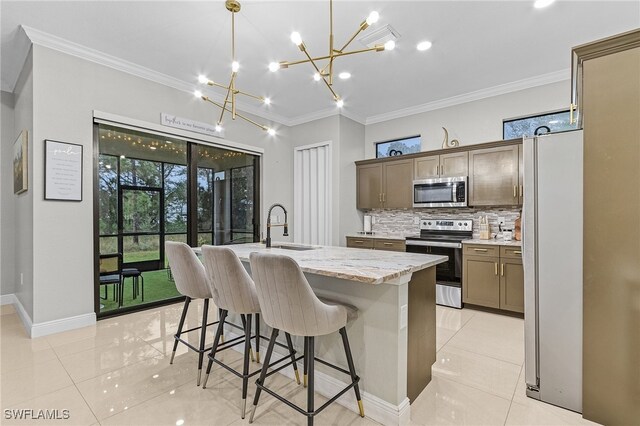 kitchen featuring a center island with sink, sink, appliances with stainless steel finishes, tasteful backsplash, and hanging light fixtures