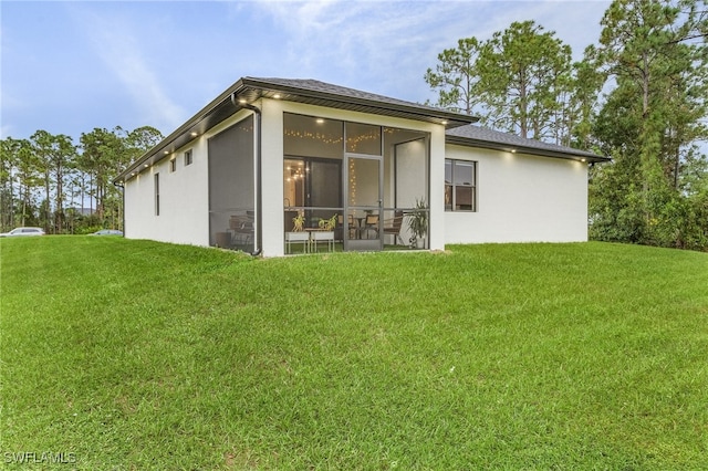 rear view of property with a sunroom and a yard