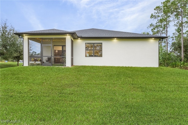 rear view of house with a lawn and a sunroom