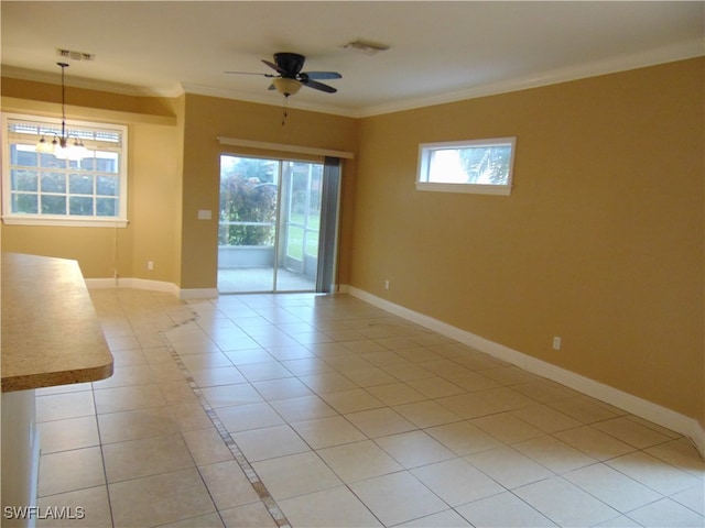 tiled spare room featuring a wealth of natural light, ornamental molding, and ceiling fan with notable chandelier