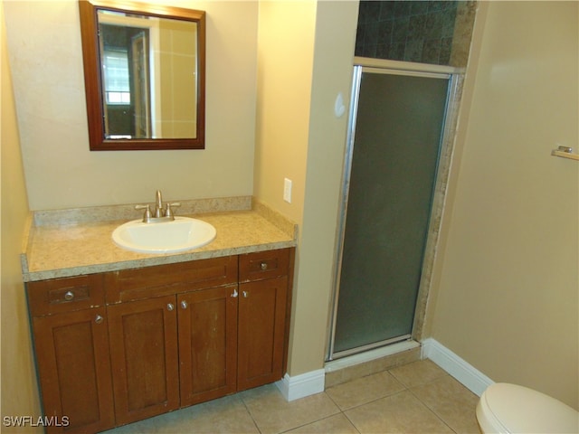 bathroom featuring tile patterned flooring, vanity, toilet, and a shower with door