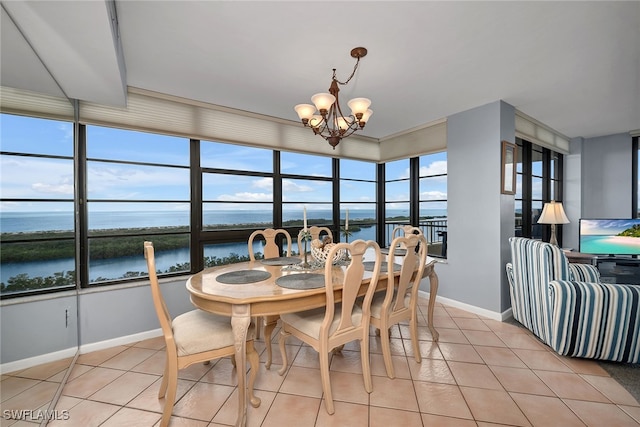 dining area featuring a water view, light tile patterned floors, and a chandelier