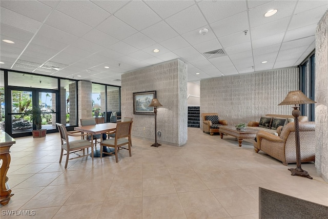 tiled dining area with a paneled ceiling and floor to ceiling windows