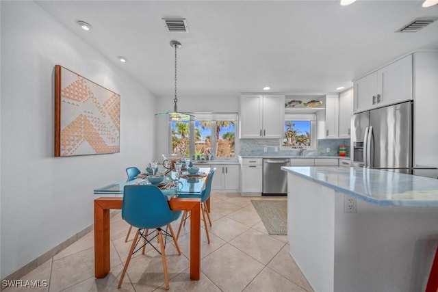 kitchen featuring decorative light fixtures, white cabinets, stainless steel appliances, and light tile patterned flooring