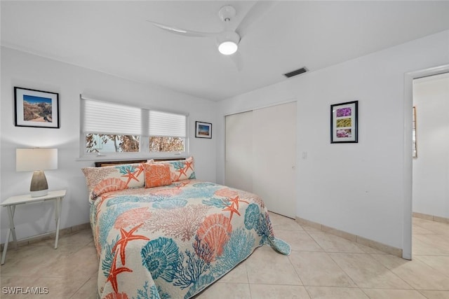 bedroom with ceiling fan, light tile patterned floors, and a closet