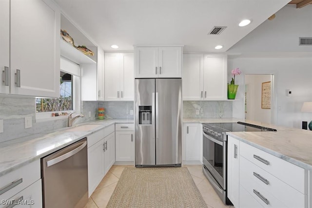 kitchen featuring light tile patterned floors, appliances with stainless steel finishes, backsplash, light stone countertops, and white cabinets