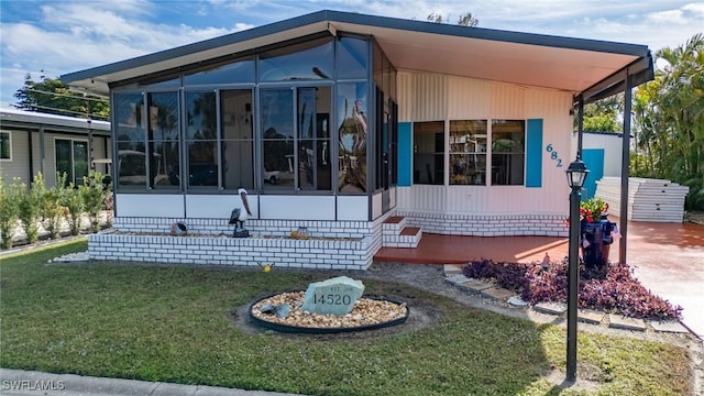 view of side of home with a sunroom and a yard