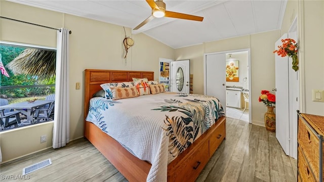 bedroom with ensuite bathroom, vaulted ceiling with beams, ceiling fan, and light hardwood / wood-style flooring