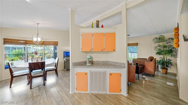 kitchen featuring pendant lighting, lofted ceiling, a chandelier, and light hardwood / wood-style floors