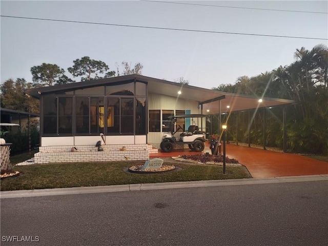 view of front of house with a carport, a sunroom, and a front yard