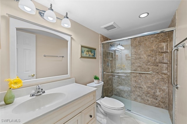 bathroom featuring toilet, vanity, tile patterned flooring, and a shower with shower door