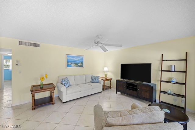 living room with a textured ceiling, ceiling fan, and light tile patterned floors