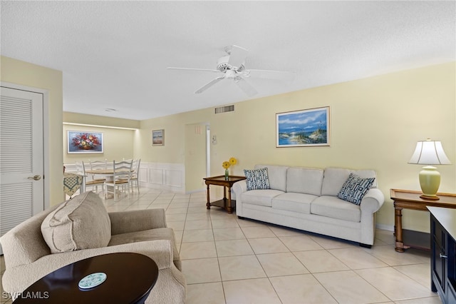 living room with light tile patterned flooring, ceiling fan, and a textured ceiling