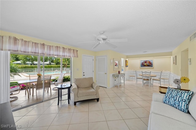 living room with light tile patterned flooring, a textured ceiling, and ceiling fan