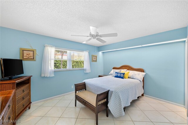 bedroom with a textured ceiling, ceiling fan, and light tile patterned floors