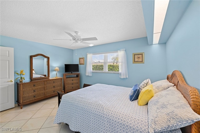 bedroom featuring a textured ceiling, ceiling fan, and light tile patterned flooring