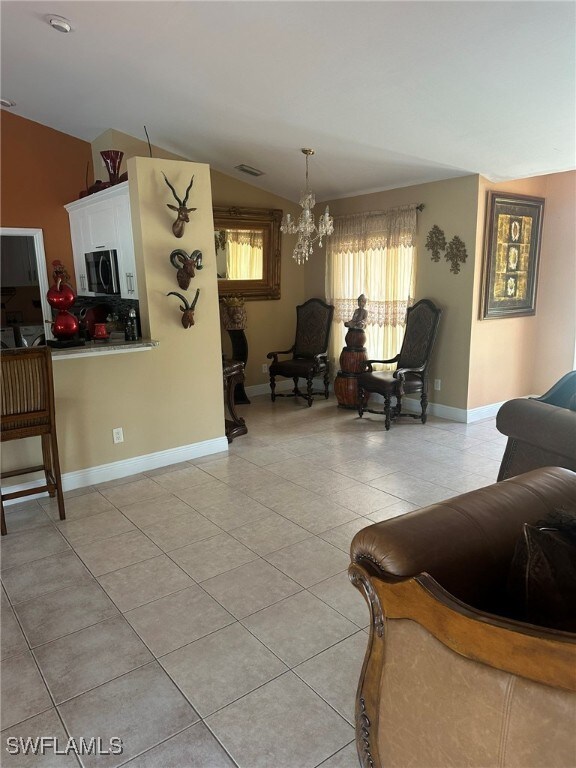 living room with a chandelier, vaulted ceiling, and light tile patterned floors