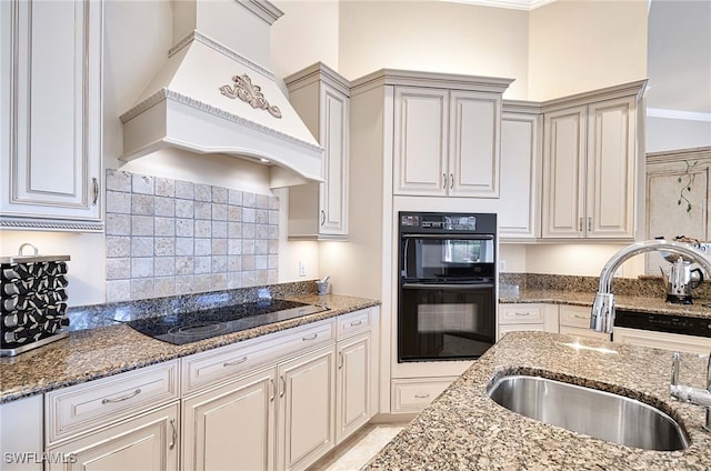 kitchen with custom exhaust hood, black appliances, crown molding, sink, and dark stone countertops