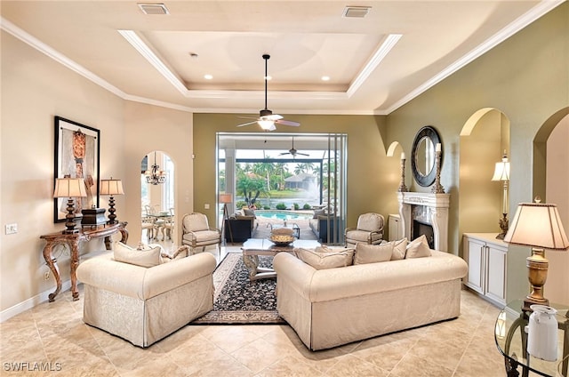 tiled living room featuring a tray ceiling, ceiling fan, and ornamental molding