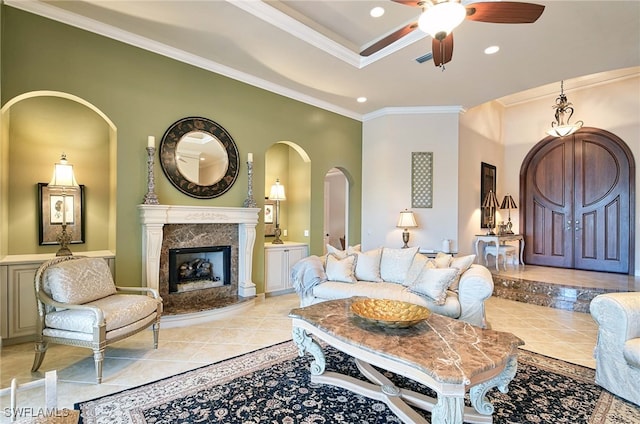 tiled living room featuring a high end fireplace, ceiling fan, and crown molding