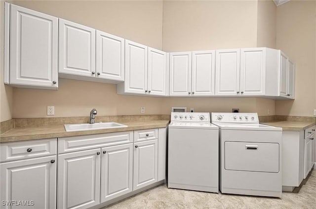 laundry area featuring washer and dryer, cabinets, and sink