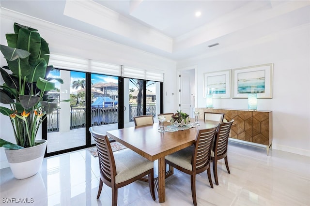 dining area featuring light tile patterned floors, a raised ceiling, and ornamental molding