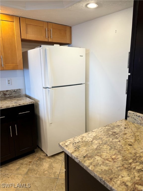 kitchen featuring white refrigerator and light stone counters