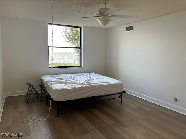 bedroom featuring a textured ceiling, ceiling fan, and dark wood-type flooring