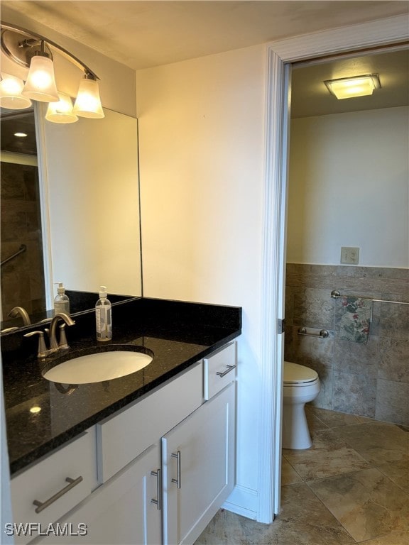 bathroom with vanity, toilet, and tile walls