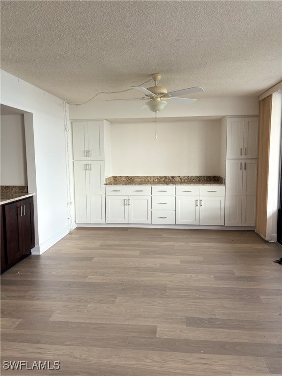 kitchen with white cabinets, light wood-type flooring, a textured ceiling, and ceiling fan