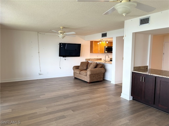 living room featuring a textured ceiling, hardwood / wood-style flooring, and sink