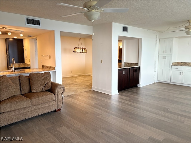 living room with hardwood / wood-style floors, a textured ceiling, ceiling fan, and sink