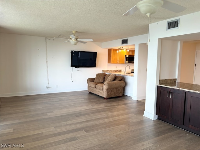 living room featuring sink, a textured ceiling, and hardwood / wood-style flooring