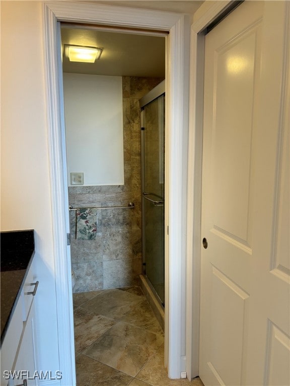 bathroom with vanity, a shower with shower door, and tile walls