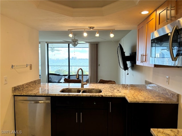 kitchen featuring kitchen peninsula, appliances with stainless steel finishes, light stone countertops, and sink