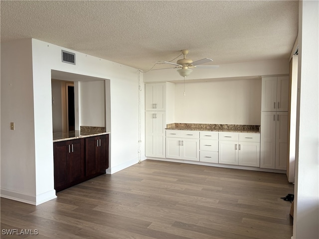 kitchen with a textured ceiling, dark brown cabinetry, ceiling fan, hardwood / wood-style floors, and white cabinetry