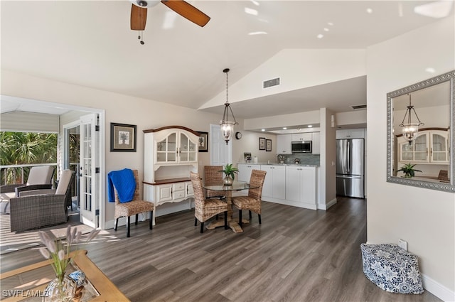 dining space featuring dark wood-type flooring, ceiling fan with notable chandelier, and high vaulted ceiling