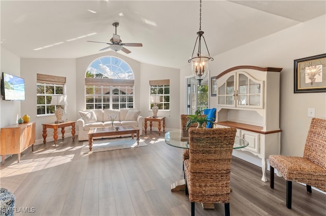 living area featuring hardwood / wood-style floors, ceiling fan with notable chandelier, and vaulted ceiling