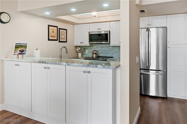 kitchen featuring light stone counters, appliances with stainless steel finishes, dark hardwood / wood-style floors, decorative backsplash, and white cabinets