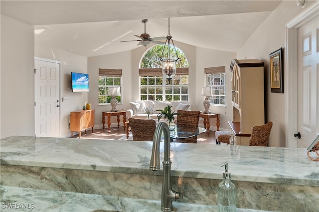 dining area with ceiling fan with notable chandelier and vaulted ceiling