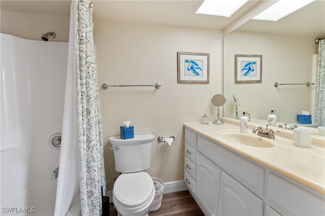 bathroom featuring hardwood / wood-style flooring, a shower with curtain, a skylight, vanity, and toilet