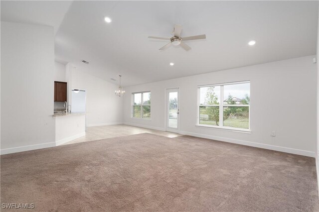 unfurnished living room with ceiling fan with notable chandelier, light colored carpet, lofted ceiling, and sink